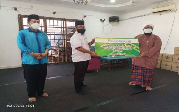 Dr Asmadi menyerahkan bantuan kepada Pengetua Maahad Tahfiz Darul Izzah, Mohd Fadhil Noor pada siri lawatan ziarah serta penyerahan sumbangan kepada tiga maahad tahfiz di sini pada Khamis. - Foto Facebook Muip