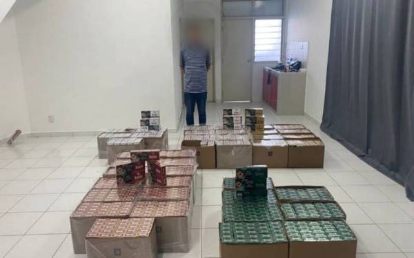 Suspek dan rokok seludup yang dirampas dalam serbuan di sebuah rumah di Taman Desa Tebrau pada Khamis.