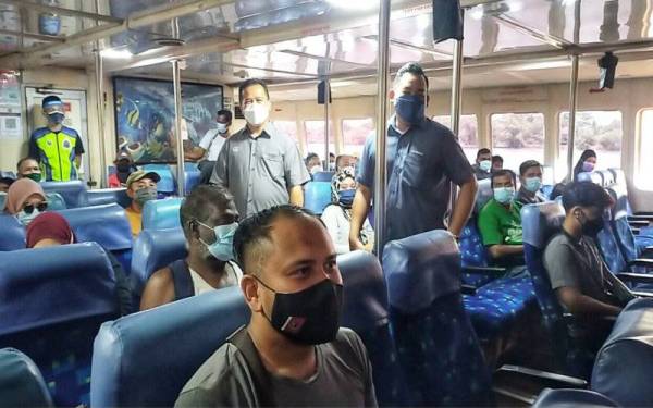 Mohd Firdaus (kanan) dan Azman (dua,kanan) memantau penumpang yang menaiki feri untuk ke Langkawi di Jeti Kuala Kedah pada Jumaat.
