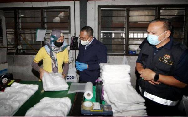 Awang Hashim (tengah) bertanyakan sesuatu kepada pekerja kilang ketika menyertai Operasi Pematuhan Akta 446 dan Pelan Pemulihan Negara (PPN) Akta 342 di kawasan kilang Perindustrian Kamunting pada Jumaat.