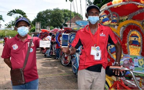 Pengayuh beca Sulaiman Abd Wahab, 62, (kanan) dan Hararana Jeet Singh, 66, menunjukkan sijil vaksinasi Covid-19 masing-masing dan mereka telah menerima dua dos lengkap vaksin berkenaan ketika ditemui selepas Program Penyerahan Kit Bantuan Makanan dan Kit Cegah Covid-19 kepada Pengayuh Beca Melaka di Bandar Hilir pada Jumaat. - Foto Bernama