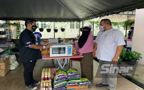 Muhammad Farid (kiri) menerima hadiah kejutan dari Kelab Kebajikan Asnaf Kelantan yang memberikannya sebuah pembakar roti.