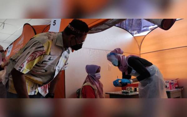 Rosol (kiri) melihat proses pemberian vaksin Covid-19 kepada seorang penerima di sini pada Sabtu.