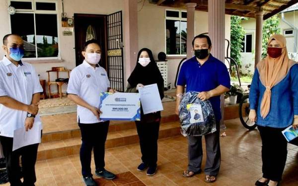 Wan Saiful (dua dari kiri) menyerahkan surat WPP kepada Nur Anis Nadia (tengah) di rumahnya di Kampung Hutan Terabak, Paya Kemunting, Jitra pada Sabtu. Turut sama, Wan Zawiah (kanan) dan Fauzi Azli (kiri).