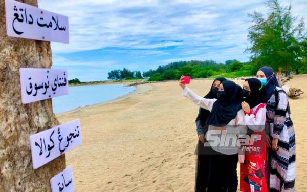 Pengunjung yang bergambar di Pantai Nusuk di Tanjung Kuala, Sabak, Pengkalan Chepa, Kota Bharu sementara Pantai Nami di Bachok dapat dilihat berada di hujung pantai berkenaan. PHOTO: SINAR HARIAN