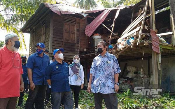 Saarani (tengah) meninjau sebuah rumah yang terjejas akibat ribut ketika lawatannya ke sekitar daerah Manjung pada Ahad.