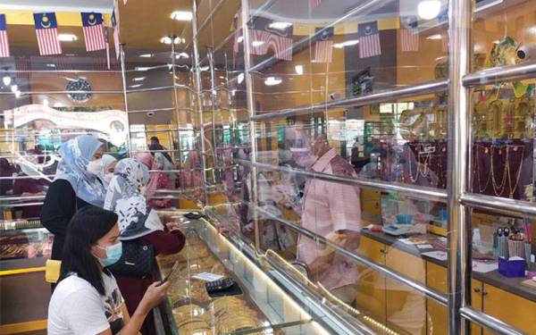 Pengunjung kedai emas Sri Gelugor, Kuala Terengganu sedang melihat koleksi barang emas yang dipamerkan di premis tersebut