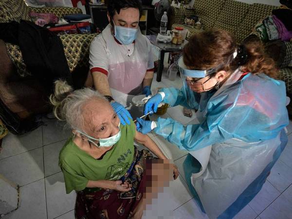 Sukarelawan Persatuan Bulan Sabit Merah (PBSM) negeri Dr Melissa memberi suntikan vaksin kepada Che Nu Ali, 74, merupakan pesakit strok di rumahnya dekat Taman Free School pada Program Vaksinasi Dari Rumah Ke Rumah hari ini.