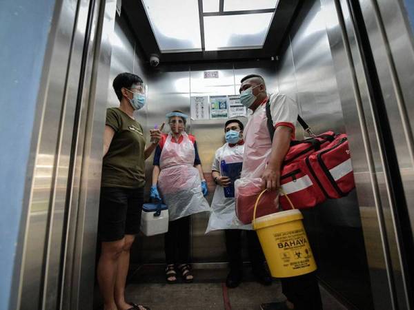 Sukarelawan Persatuan Bulan Sabit Merah (PBSM) negeri bersiap sedia untuk memberi suntikan vaksin kepada seorang orang kurang upaya (OKU) Syndrome Down pada Program Vaksinasi Dari Rumah Ke Rumah hari ini.