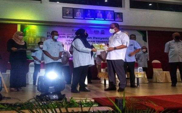 Shamsaini (kiri) menyerahkan Draf RT Daerah Raub 2035 (Penggantian) kepada Wan Rosdy sempena majlis perasmian program publisiti dan penyertaan awam draf itu di Dewan Jubli Perak, Raub pada Isnin.