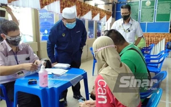 Mohd Akmal (berdiri, kiri) bertanyakan sesuatu kepada pelajar untuk program vaksinasi ketika mengadakan lawatan di PPV Sekolah Izzuddin Shah pada Selasa.