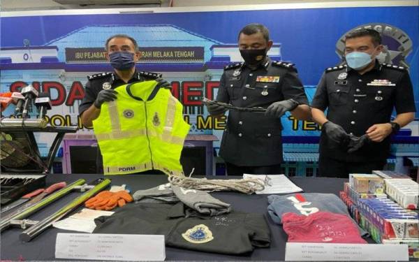 Abdul Majid (kanan) menunjukkan jaket keselamatan polis ketika sidang akhbar di IPD Melaka Tengah, Banda Hilir, di sini, pada Selasa.