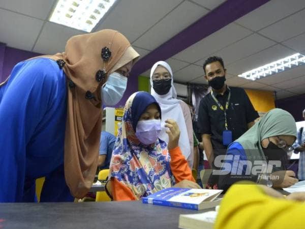 Nolee Ashilin (kiri) beramah mesra dengan pelajar yang mengikuti pengajaran dan pembelajaran di rumah (PdPR) menerusi telefon bimbit di Perpustakaan Komuniti PPR Seri Kepayang.