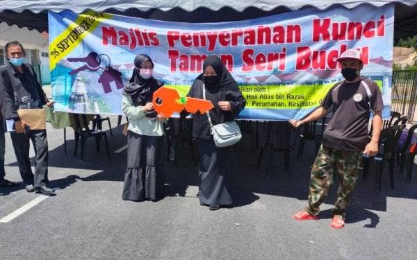 Mat Sabri (kiri) bersama pemilik rumah yang memperoleh replika kunci sempena Program Penyerahan Kunci Taman Seri Buchu, Kuala Nerus pada Selasa