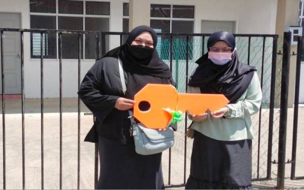 Azima Mohd (kiri) dan anaknya, Nur Athirah Najwa, 21 ( kanan) menunjukkan replika kunci diterima di hadapan rumah mereka