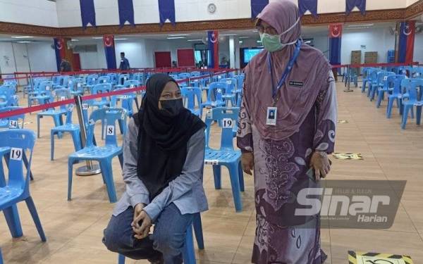 Dr Surinah (kanan) bertanya khabar Nor Aliyah selepas menerima suntikan vaksin di PPV Dewan Jubli Intan Pontian pada Selasa.