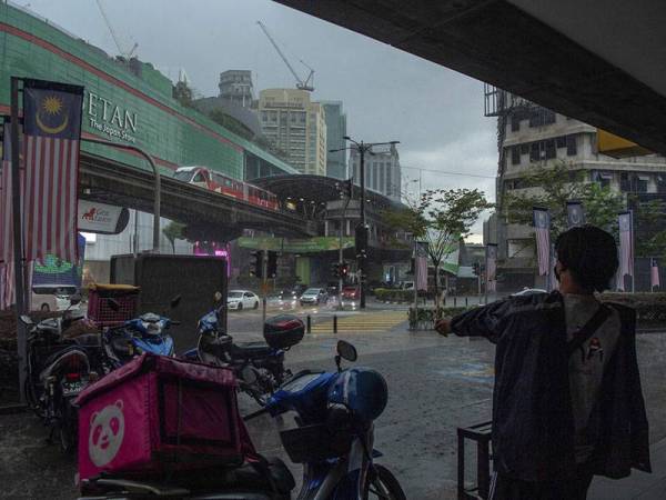 Kelihatan penghantar makanan memakai baju hujan sebelum melakukan penghantaran pesanan kepada pelanggan ketika tinjauan di sekitar ibu kota hari ini.