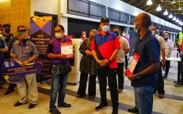 Shahidan (dua dari kanan) beramah mesra dengan penjaja pada sesi penyerahan kunci dan lesen perniagaan di Pusat Penjaja Pekan Sungai Besi @ D'laman Rasa, Kuala Lumpur pada Rabu.