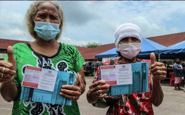 Penduduk Kampung Orang Asli Punan, Langam Meripin (kiri) bersama Budi Chentek menunjukkan isyarat bagus dan kad vaksinasi mereka pada Program Imunisasi Covid-19 Kebangsaan Daerah Mersing di Sekolah Kebangsaan Punan, baru-baru ini. - Foto Bernama
