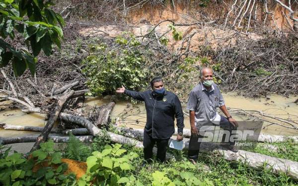 Muhammad Arafat (kiri) bersama Abdul Aziz menunjukkan keadaan sungai yang dipenuhi pokok hasil tebangan syarikat kontraktor yang terlibat dalam perlombongan kaolin di Kampung Kolam, Tanjung Rambutan.