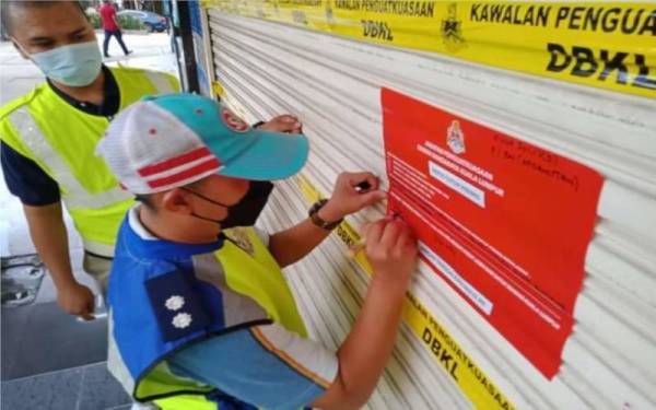 Penguat kuasa DBKL menampal notis penutupan di pintu salah sebuah premis perniagaan dalam operasi di Kuala Lumpur pada 16 sehingga 30 September lalu. - Foto Facebook DBKL