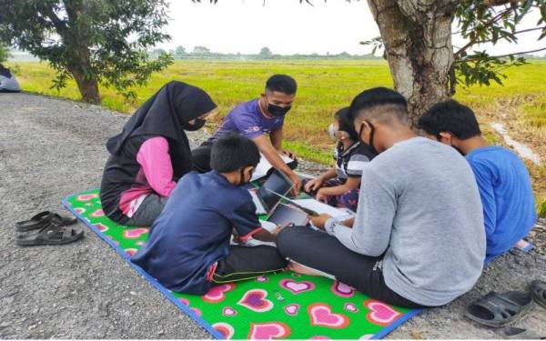 Nur Syamira Awatif (kiri) mengikuti kelas PdPR bersama rakan- rakannya di kawasan sawah padi di Kampung Raja di sini.
