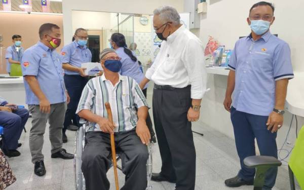 Noh (dua dari kanan) bertanya sesuatu kepada salah seorang penerima faedah pemulihan pada Majlis Perasmian Ulang Tahun Ke-50 Perkeso Cawangan Tanjong Karang pada Jumaat.
