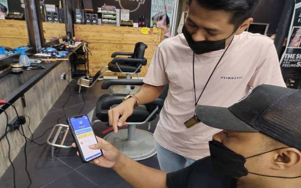 Pekerja di kedai gunting rambut sekitar Shah Alam sedang menyemak status sijil vaksinasi Covid-19 pelanggan.