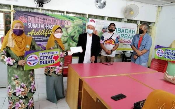 Radziah (dua dari kiri) menyampaikan sumbangan wang tunai kepada wakil Surau Al Husany pada Sabtu.