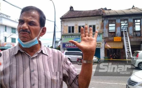 Seenivasagam di hadapan premis miliknya yang musnah akibat kebakaran tersebut.