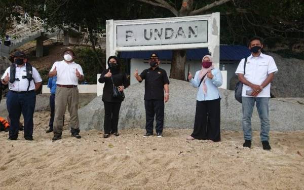 Ahmad (tengah) dan Haslina(tiga, kanan) bergambar papan tanda Pulau Undan ketika lawatan kerja di pulau itu pada Sabtu.
