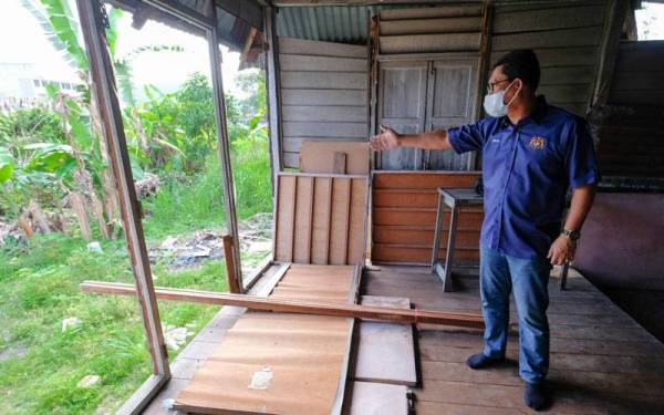 Ahmad Faizal melihat keadaan di dalam rumah ketika menziarah keluarga asnaf di Jalan Raja Kampung Manjoi hari ini. Foto Bernama