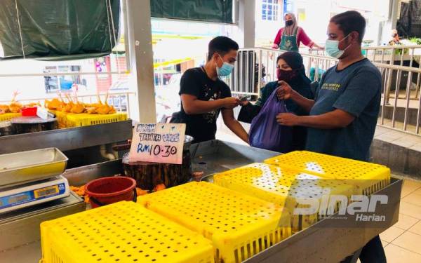 Nafidah (tengah) membeli ayam kuning dengan Mohd Nazwan di Pasar Cabang Tiga, Pengkalan Chepa, Kota Bharu.