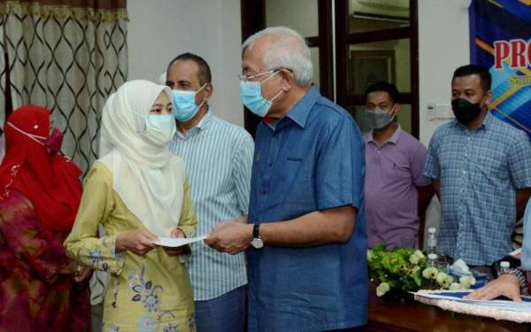 Mahdzir (tiga dari kanan) menyampaikan sumbangan kepada seorang pelajar pada majlis simbolik di Kampung Padang Kerasak, Kuala Nerang pada Ahad.