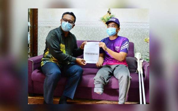 Haim Hilman (kiri) menyerahkan surat tawaran kemasukan ke UUM kepada Nek Muhammad Sofwan Najim di rumahnya di Taman Nuri pada Khamis.