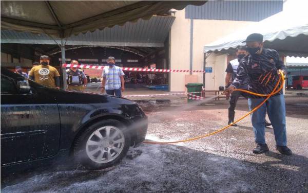 Mohd Yusof (kanan) turut tidak ketinggalan membantu membersihkan kenderaan petugas hadapan yang menyertai program tersebut pada Ahad.