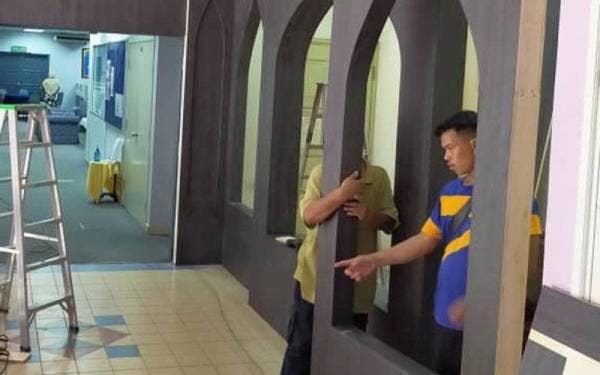 Pekerja Muhamad Zamzuri sedang memasang dinding yang ditempah pelanggan.