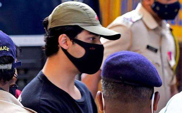 Aryan Khan dikawal oleh pegawai penguat kuasa di luar pejabat Biro Kawalan Narkotik, di Mumbai pada 3 Oktober lalu. - Foto AFP