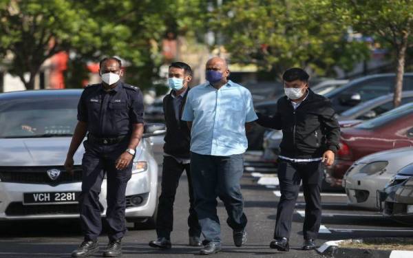 Tertuduh diiring polis ketika hadir di Mahkamah Sesyen Seremban pada Rabu atas pertuduhan pecah amanah berkaitan patung kuil tiga tahun lalu.