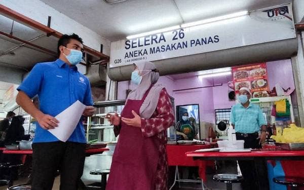 Mohamad Yusrizal (kiri) meninjau dan mendengar keluhan Salmah yang kembali berniaga sejak dua minggu lalu di Medan Selera Majlis Bandaraya Alor Setar (MBAS), Alor Setar pada Rabu.