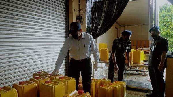 Saharuddin (kiri) menunjukkan botol minyak masak yang ditemui di dalam premis berkenaan.