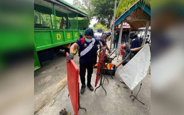 Anggota penguatkuasa DBKL merampas barangan penjaja yang didapati melanggar syarat ditetapkan. Foto ihsan Facebook DBKL.