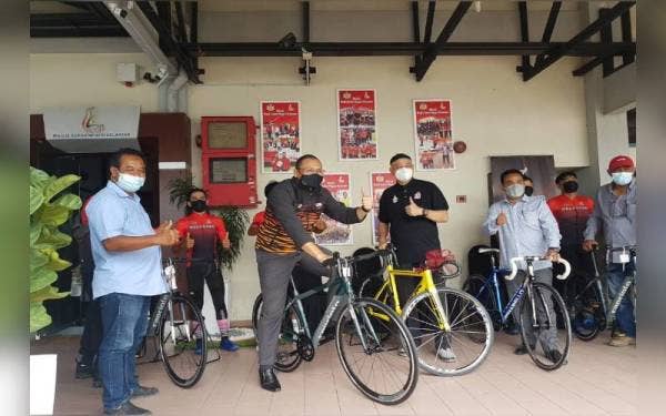 Fared (empat dari kanan) dan Imran (tengah) melakukan gimik penyampaian basikal berkenaan di bangunan MSN Telipot, di sini.