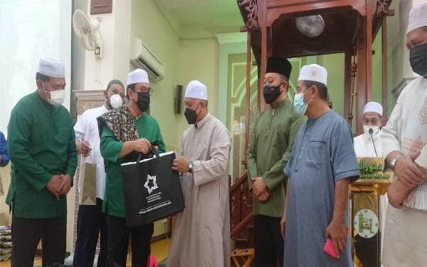 Sulaiman (dua dari kiri) menyampaikan sumbangan kepada salah seorang ahli jawatankuasa Masjid Nurul Hidayah di Batu Berendam di sini pada Jumaat.