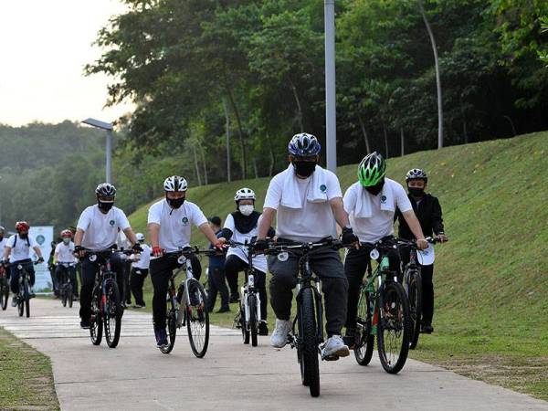 Menteri Tenaga dan Sumber Asli Datuk Seri Takiyuddin Hassan (hadapan) mengayuh basikal pada Program Berbasikal Penghijauan Malaysia sempena Hari Sukan Negara di Sisiran Tasik Presint 19 hari ini.