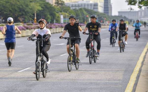 Wanita dan lelaki menyertai aktiviti berbasikal pada sambutan Hari Sukan Negara 2021 (HSN2021) di Putrajaya hari ini.