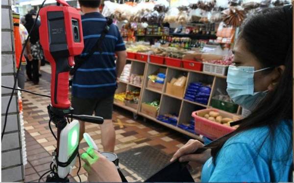 Seorang individu mengimbas token TraceTogether yang digunakan untuk memasuki mana-mana tempat awam bagi mengesan kontak.
- Foto: AFP