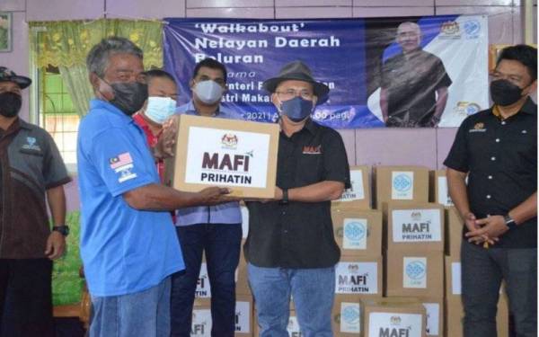 Ronald (tengah) menyerahkan sumbangan bakul makanan kepada ahli nelayan PNK Beluran