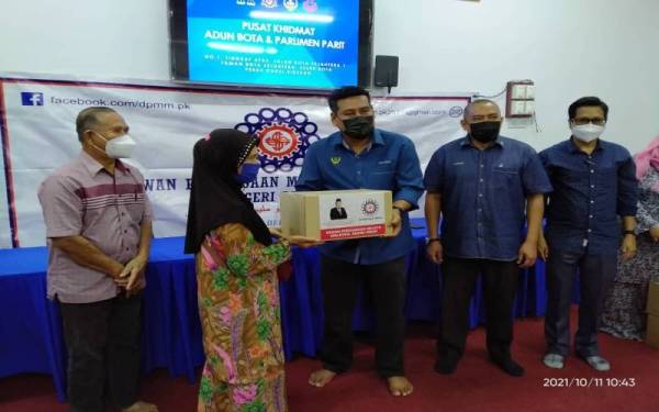 Khairul Shahril (tengah) menyampaikan kotak makanan DPMM Perak kepada penerima di Pusat Khidmat ADUN Bota di Bota Kanan, Parit pada Isnin.