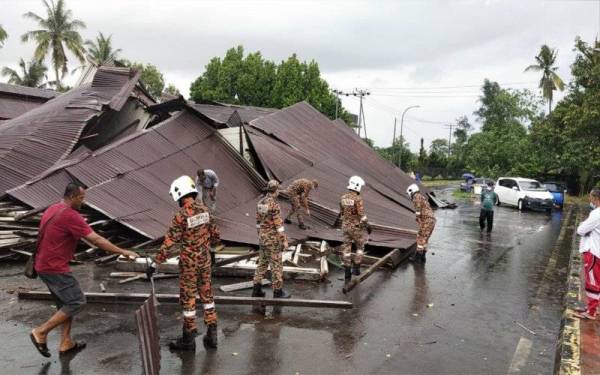Pasukan bomba membuat kerja pembersihan dan mengalih serpihan kayu bangunan kedai yang runtuh di Pekan Kimanis, Papar.